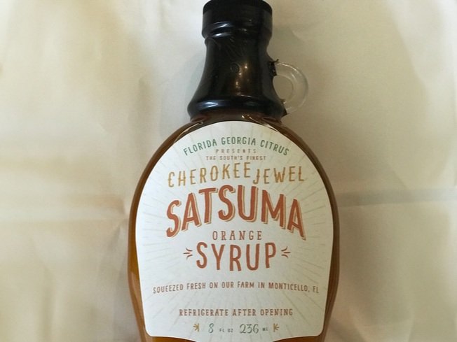Satsuma orange syrup in a glass bottle labeled "Cherokee Jewel," sourced from Florida Georgia Citrus, featuring a rustic design and instructions to refrigerate after opening.